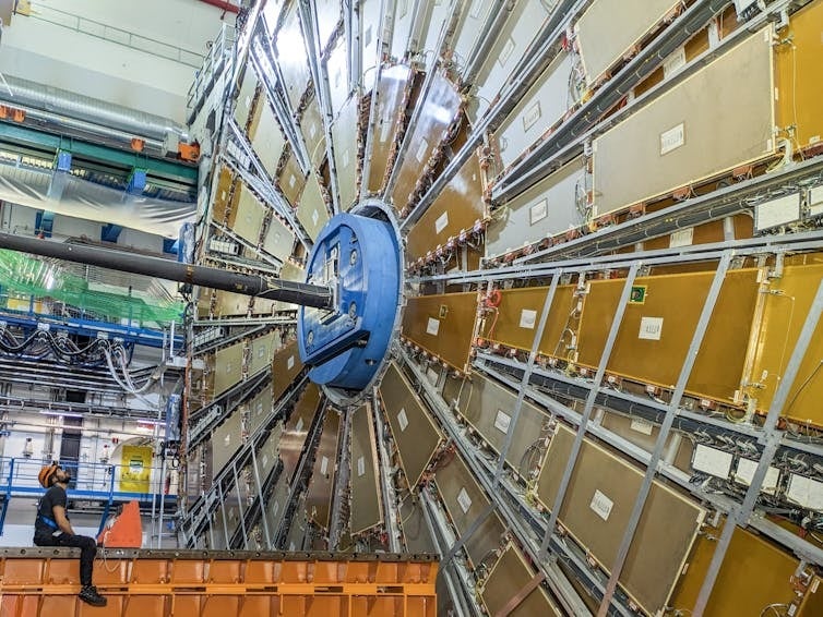 One side of the ATLAS detector at the Large Hadron Collider. The technician on the left is facing one of the wheels of the muon chambers, sensors designed to detect and measure muons. Credit: Ana Peixoto, ATLAS experiment at CERN.