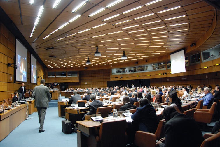 A semicircle-shaped room full of people sitting at tables.
