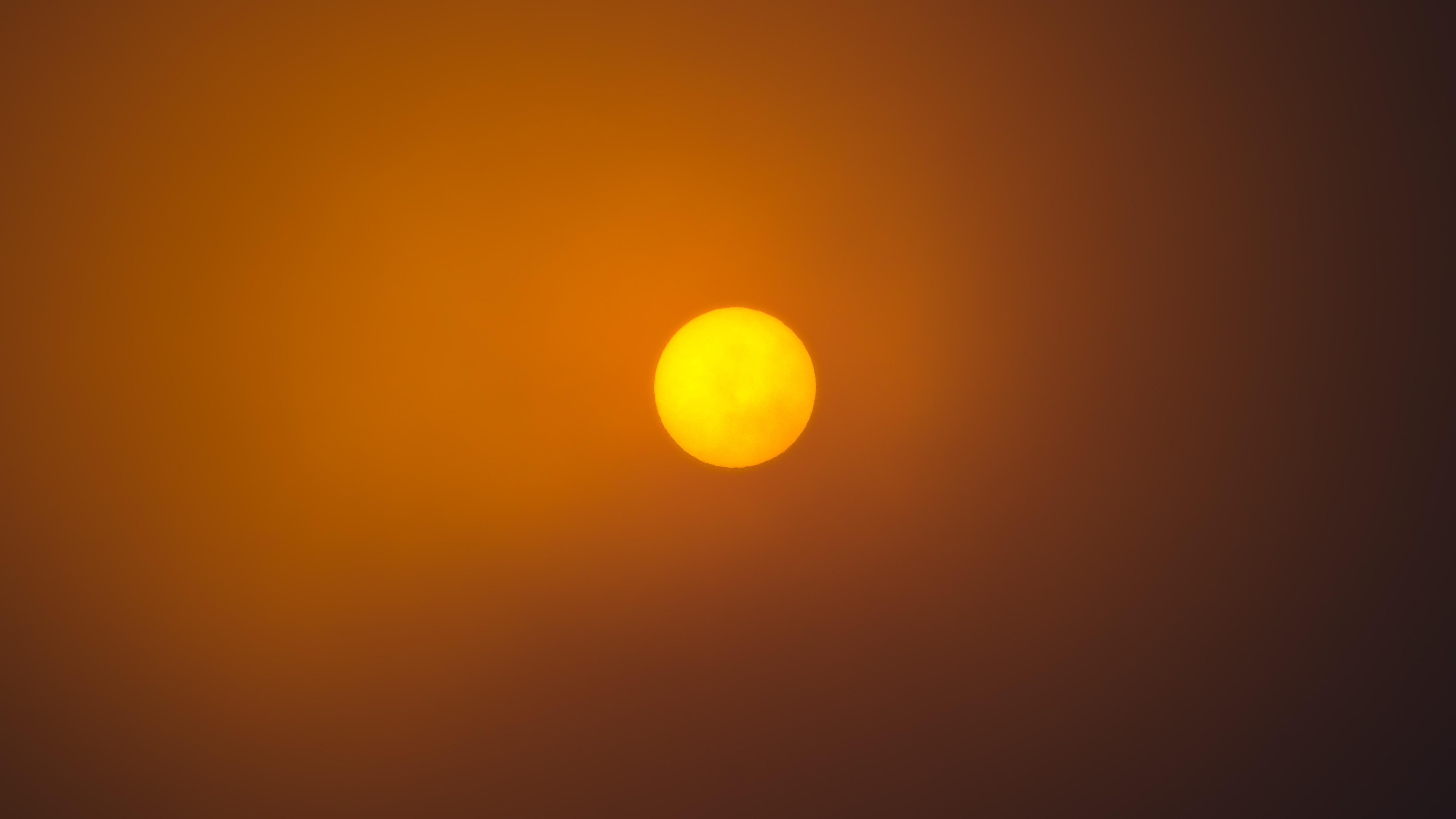 The orange disk of the sun, darkened by smoke or clouds