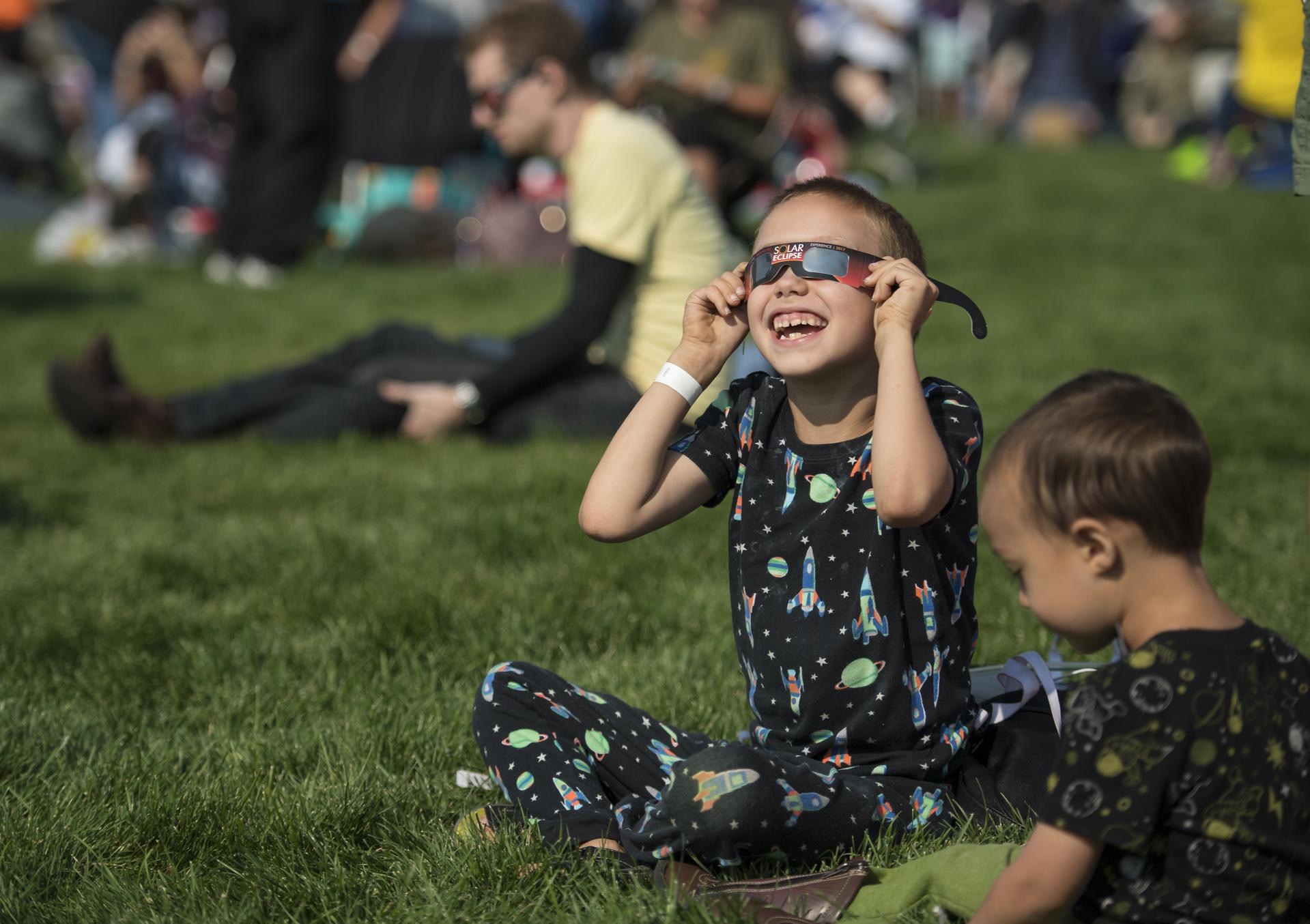 A boy watches the total solar eclipse through protective glasses in Madras, Oregon on Monday, Aug. 21, 2017. Credit: NASA/Aubrey Gemignani
