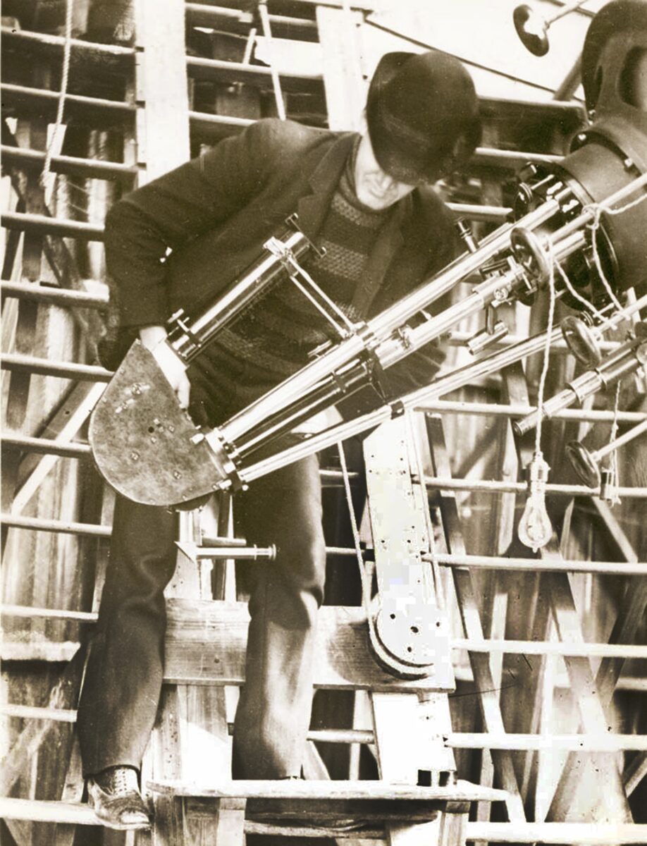 Slipher stands with the Brashear spectrograph, mounted on the 24-inch Clark Telescope, with which he made his many spectroscopic discoveries — including his observations of multiple spiral nebulae, most of which were rushing away from Earth at great speed, signaling the expansion of the universe.