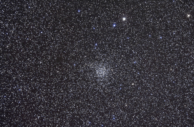 Image of a densely populated star field showing the open star cluster NGC 7789, also known as Caroline’s Rose Cluster, situated in the constellation Cassiopeia. The image is filled with countless small stars, and the central cluster appears as a slightly more concentrated region of stars forming a subtle rose-like pattern. The background is a deep black space with thousands of bright and faint stars of varying colors, including white, blue, and yellow hues.