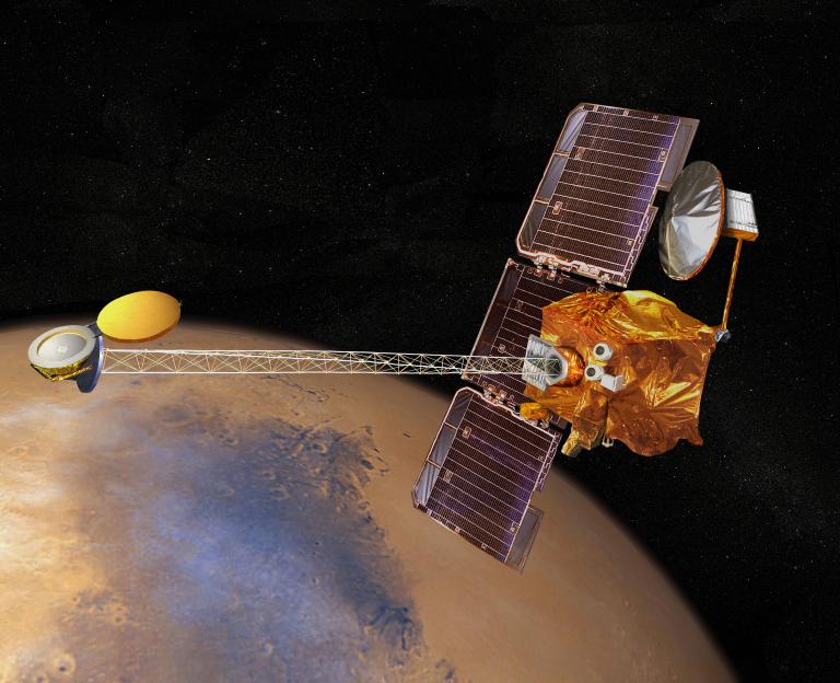 An artistic color rendering shows a boxy, gold-foil wrapped spacecraft with large, dark grid-patterned solar panels extended vertically on the right side of the frame. A long, silver lattice boom stretches horizontally to the left, connecting to a set of smaller, rounded gold and silver instruments. The spacecraft floats in a stark black void speckled with faint white stars, positioned directly above the curved, brightly lit surface of a tan and light orange planet.