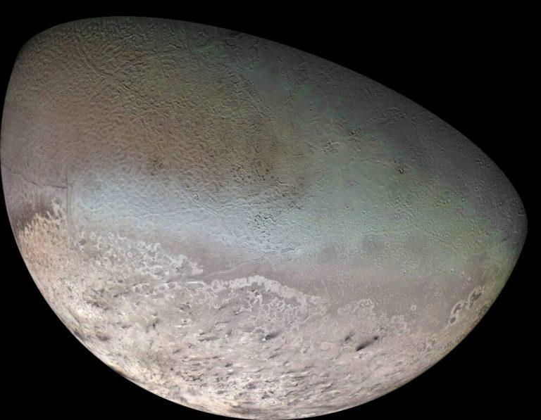 A crescent-shaped view of a planetary body fills most of the frame against a solid black background. The upper portion displays a subtle, greenish-blue textured surface covered in faint crisscrossing ridges and dimples, while the lower region transitions into a lighter, pale grey terrain marked by dark streaks and dimpled depressions. Soft, directional sunlight highlights the contrast between the smoother top area and the rugged, mottled lower polar region.