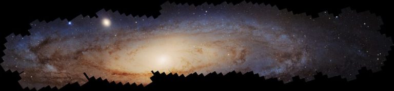 A wide, panoramic composite image displays a brightly glowing, elongated star cluster stretching horizontally across a solid black background. The center shines in warm, golden-cream light, surrounded by reddish-brown dust lanes that transition outward into dense fields of cool blue stars. The outer edges of the mosaic display a jagged, stepped border where individual rectangular sub-images meet.