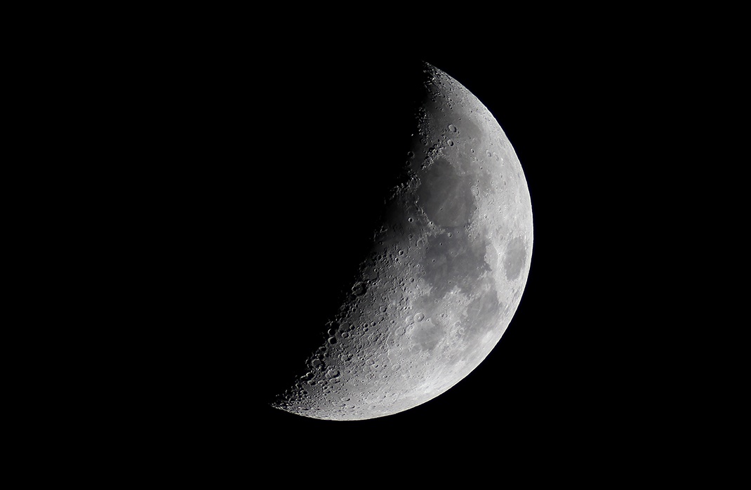 The crescent Moon with sharp crater detail visible along the terminator