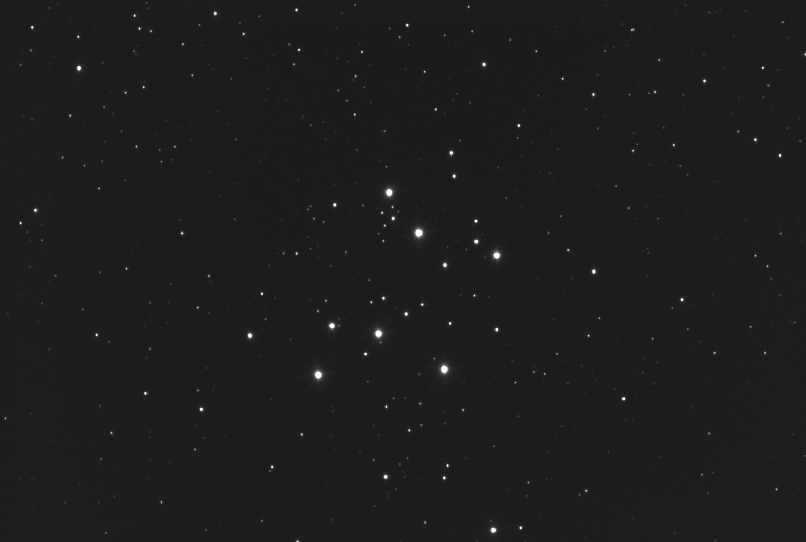 Black-and-white astrophotograph of M29, a sparse open star cluster showing roughly a dozen bright stars arranged in a loose rectangular pattern against a field of fainter background stars.