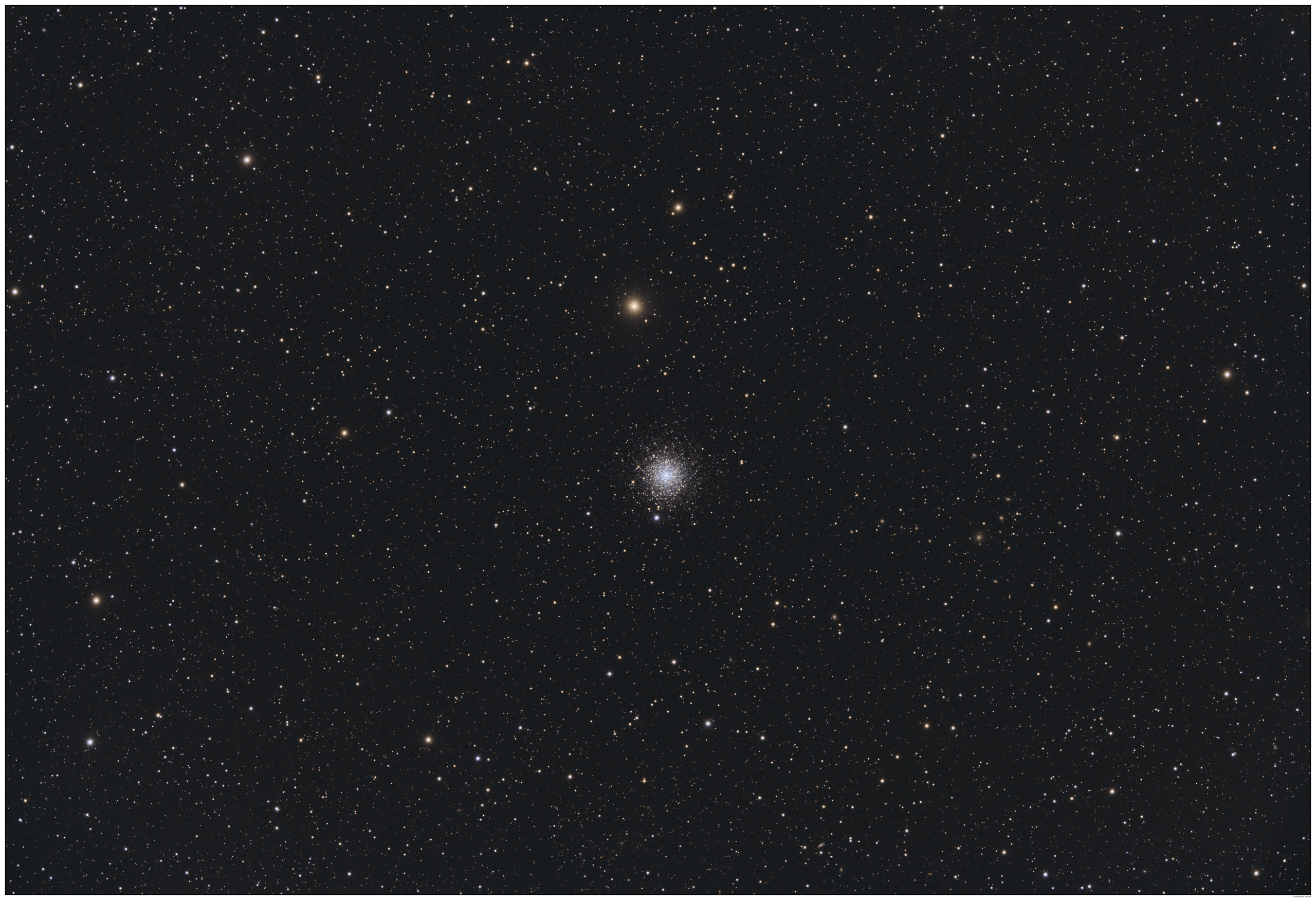 A telescopic photograph of M30, a globular cluster appearing as a compact, dense ball of white and blue-white stars near the center of the image, with a bright yellow-orange foreground star visible just above it. The cluster is set against a black sky scattered with numerous orange, yellow, and white foreground stars of varying brightness.