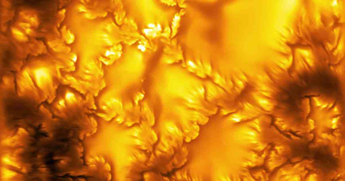 High-resolution solar image showing granular surface texture with wave-like plasma vortices curling along dark boundaries between granules.