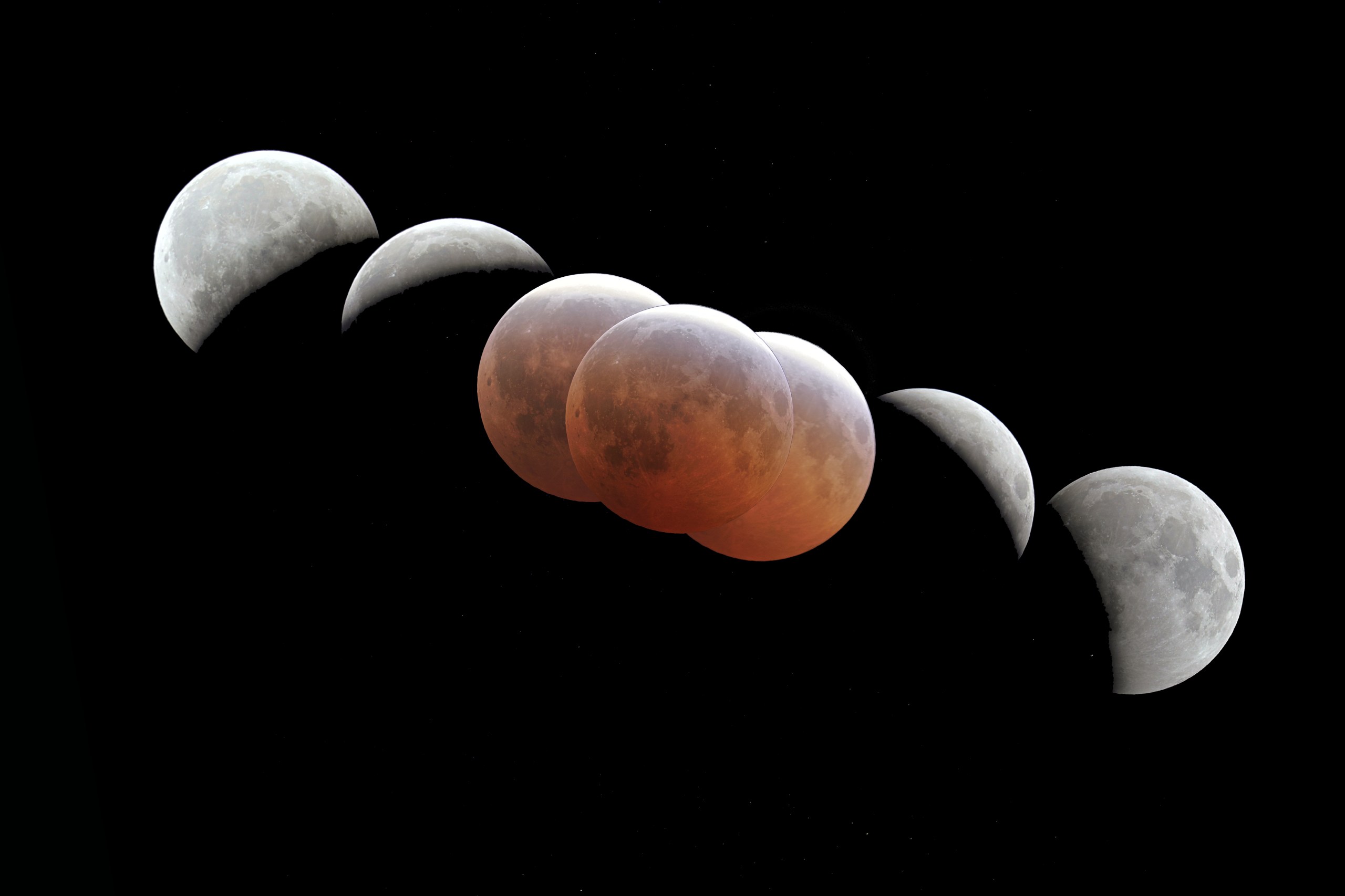 A diagonal sequence of Moon images against a black, starry sky. On the left and right the Moon appears as bright white crescent and gibbous phases; in the middle, several overlapping discs glow a dusky orange-red where the Moon sits deep within Earth's shadow.