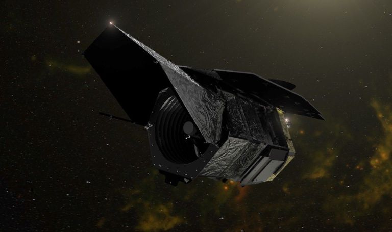 An artist's illustration of the Nancy Grace Roman Space Telescope floating in space against a starry background with a faint golden-green nebula glow. The boxy, dark-colored spacecraft is shown at an angle, with its sunshield panels extended and its primary mirror aperture visible at the front.