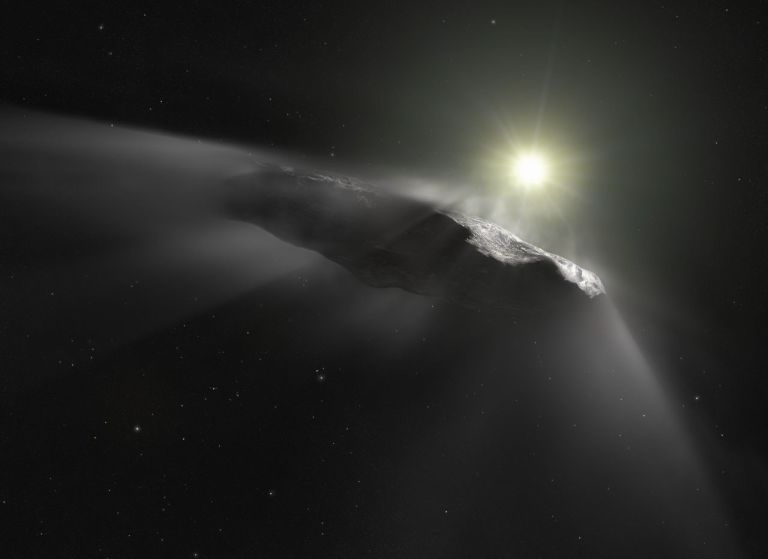 An artist's illustration of 'Oumuamua, the first known interstellar object detected passing through the solar system, depicted as a long, thin, reddish-brown elongated rock tumbling through space near a bright glowing sun. A diffuse dust or gas trail streams behind it, and the starry black background of deep space surrounds the scene.