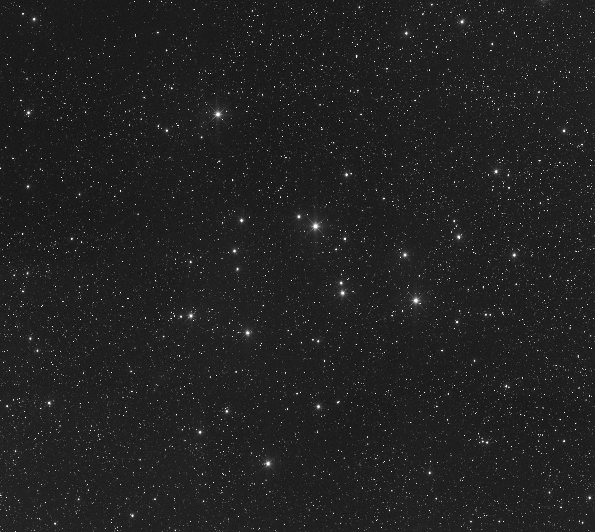 Grayscale astrophotograph of a sparse star field dominated by a loose cluster of bright stars arranged in a rough triangular pattern across the center of the frame, set against thousands of fainter background stars scattered throughout the image.