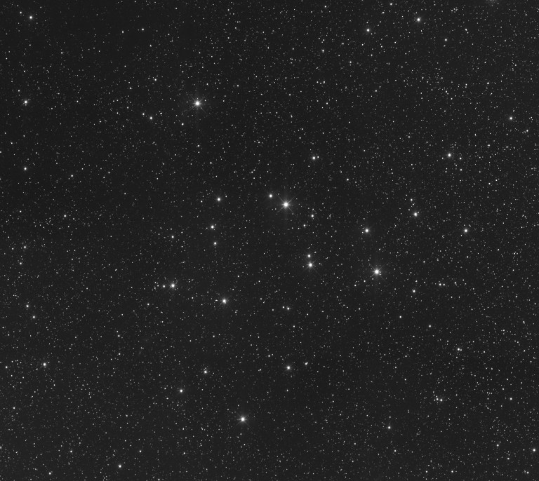 Grayscale astrophotograph of a sparse star field dominated by a loose cluster of bright stars arranged in a rough triangular pattern across the center of the frame, set against thousands of fainter background stars scattered throughout the image.