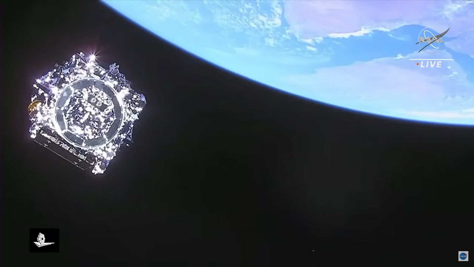 Photograph from a NASA Live broadcast showing a spacecraft against the blackness of space, its reflective solar panels and faceted gold and silver surfaces catching sunlight at left, with the curved blue limb of Earth and white clouds filling the upper right corner. The NASA logo and LIVE label appear at upper right, with a small mission logo at lower left.