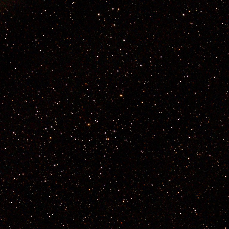 Photograph of the open cluster Collinder 463, a loose scattering of bright white and orange stars across the center of the frame, set against a black sky densely sprinkled with fainter stars.