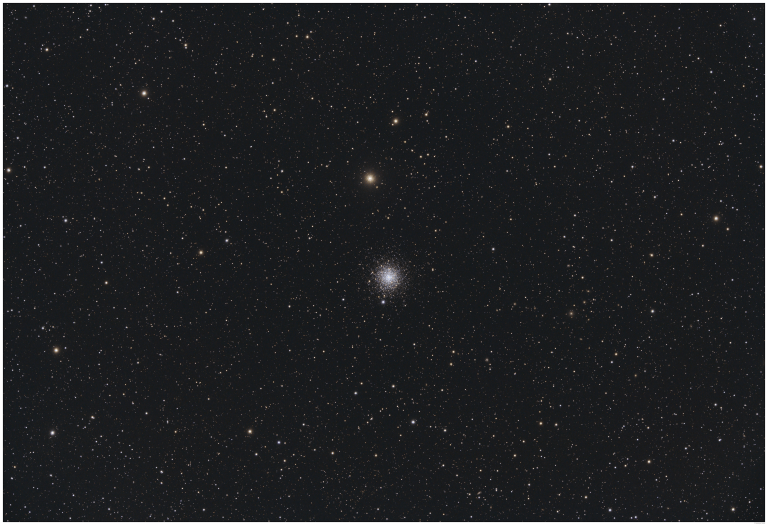 Grayscale astrophotograph of a dense globular star cluster at center, appearing as a bright concentrated ball of tightly packed stars that thins into a loose scattering of stars toward the edges, set against a sparse field of background stars.