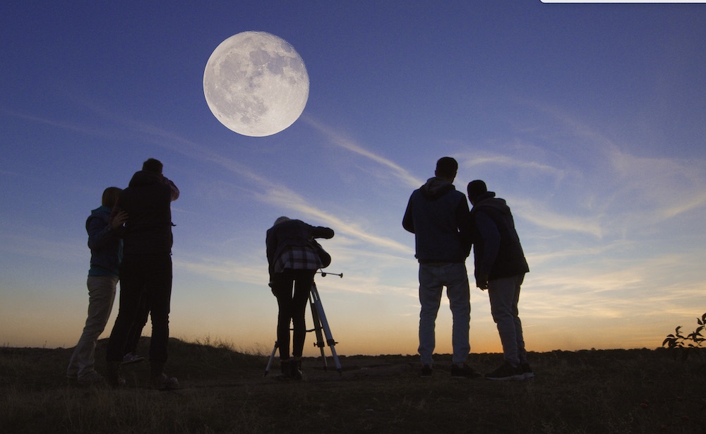 A group of people looking at the moon through telescopes