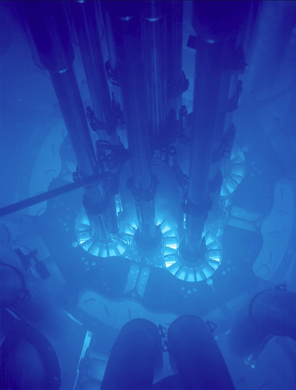 The light, called Cerenkov radiation, arises from high-energy electrons that are moving faster than light can travel through the water. 