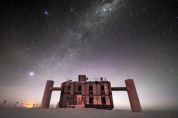 A building on a snow-covered landscape underneath a starry sky