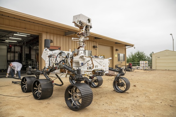 An engineering model of the Perseverance rover rolls out of its garage and into the “Mars Yard,” an outdoor area simulating martian terrain.