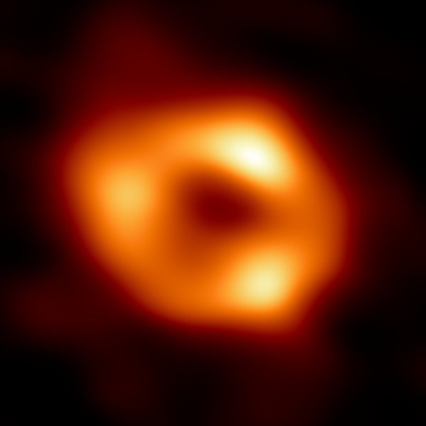 The first direct image of the Milky Way's supermassive black hole shows an orange glowing ring — gas heated as it fall into the singularity.