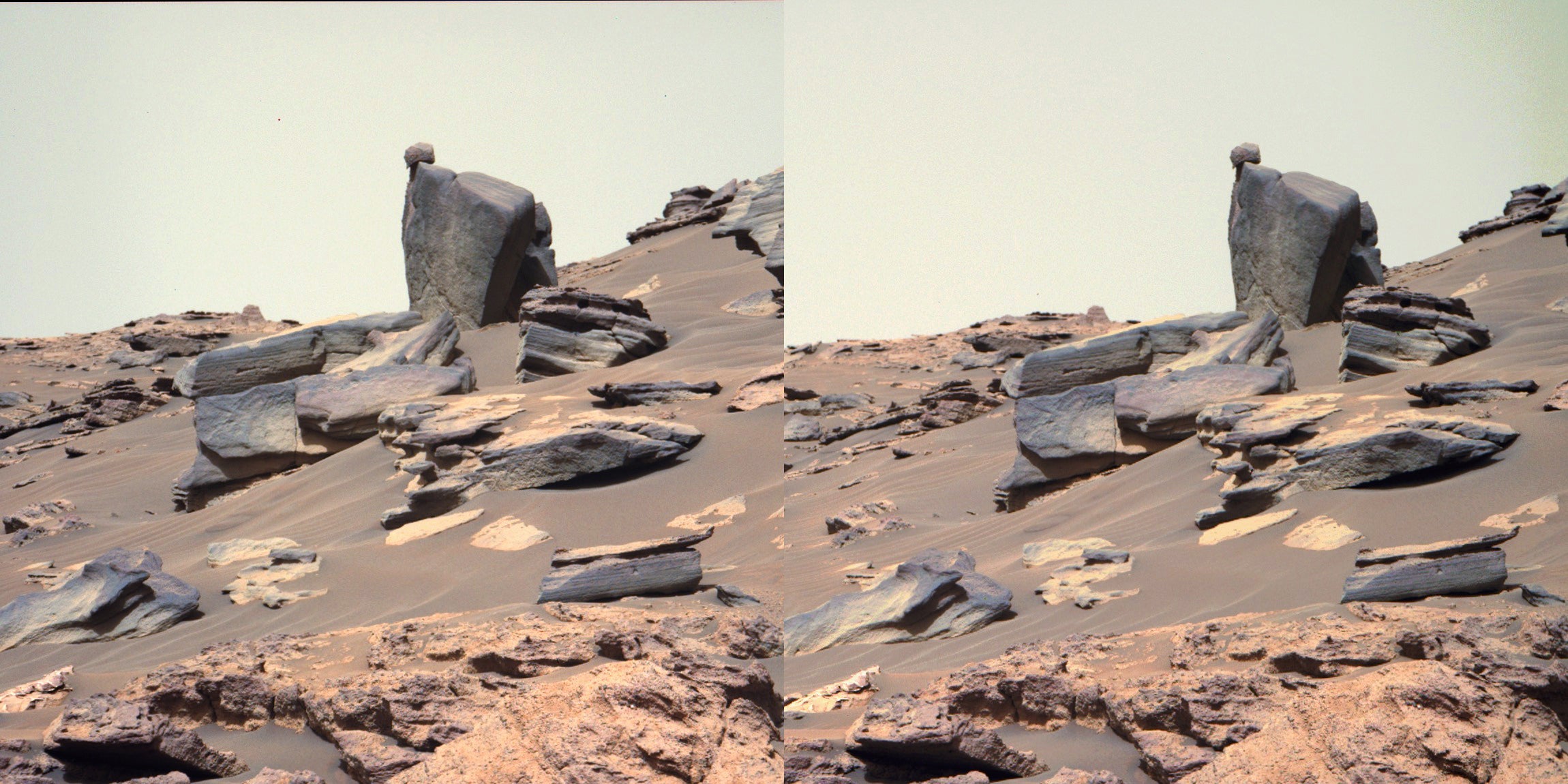 A small, rounded rock appears perfectly balanced on top of a big boulder at the center of this scene.