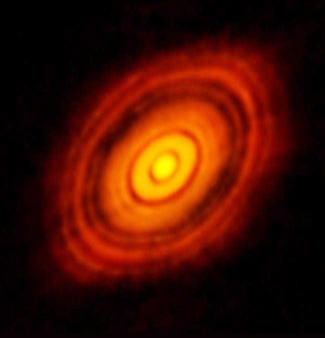 Radio observations of the young star HL Tauri reveal a massive protoplanetary disk of dust and gas surrounding the star (at the center). Nascent planets can affect the material orbiting in the disk, causing instabilities and carving out gaps. Researchers are now using AI to help identify subtle signs of planet formation within such disks.