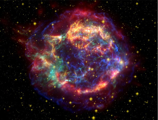 The explosive death of a massive star 325 years ago created the Cassiopeia A supernova remnant. This composite image includes infrared data from the Spitzer Space Telescope (red), visible imagery from the Hubble Space Telescope (yellow), and X-ray data from the Chandra X-ray Observatory (green and blue). The X-rays — which pose a threat to the atmospheres of nearby planets — are emitted by gases that are caught in the expanding shock wave and heated to temperatures of up to 18 million F (10 million C)
