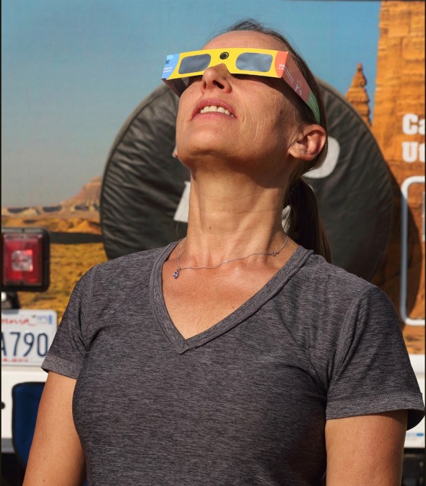 During the partial phases of the eclipse you need proper eye protection, such as the safe eclipse-viewing glasses the author’s wife, Deborah Carter, is wearing, to watch the Moon as it covers the Sun. 
