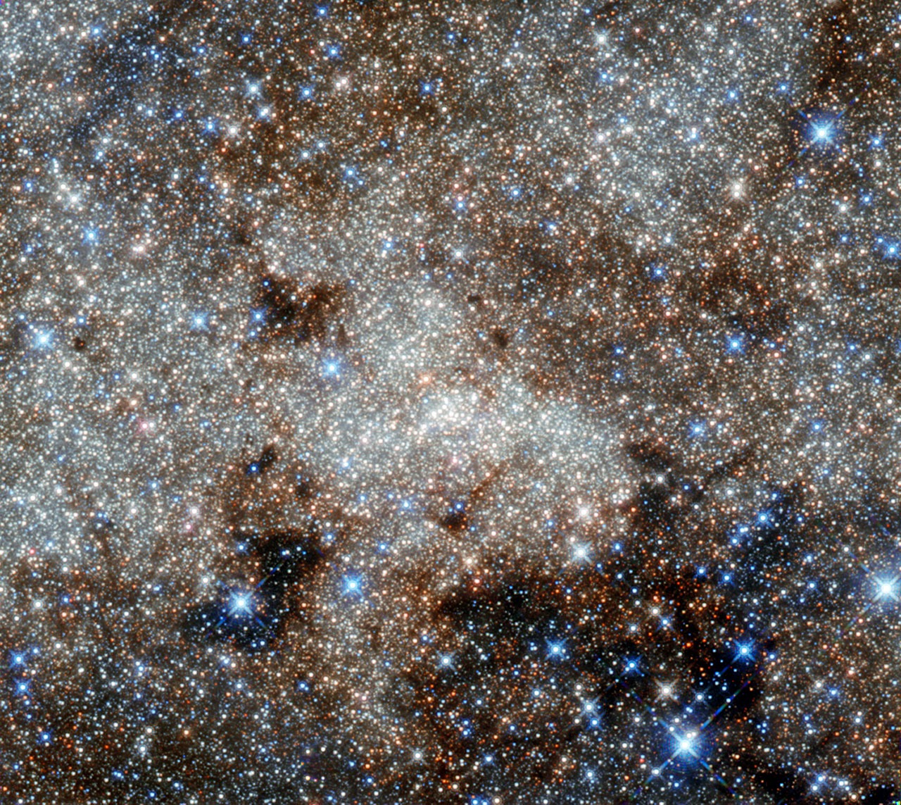 This image shows the star-studded center of the Milky Way towards the constellation of Sagittarius. The most famous cosmic object in this image still remains invisible: the monster at our galaxy’s heart called Sagittarius A*. Astronomers have observed stars spinning around this supermassive black hole (located right in the center of the image), and the black hole consuming clouds of dust as it affects its environment with its enormous gravitational pull. Credit: NASA